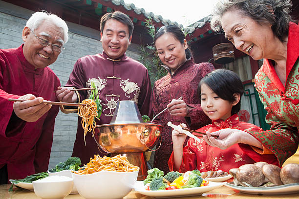 familie genießen chinesische mahlzeit in traditioneller kleidung - chinese cuisine stock-fotos und bilder