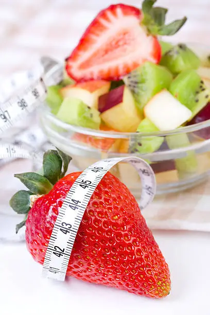 Fruit salad in white plate with measure tape, closeup