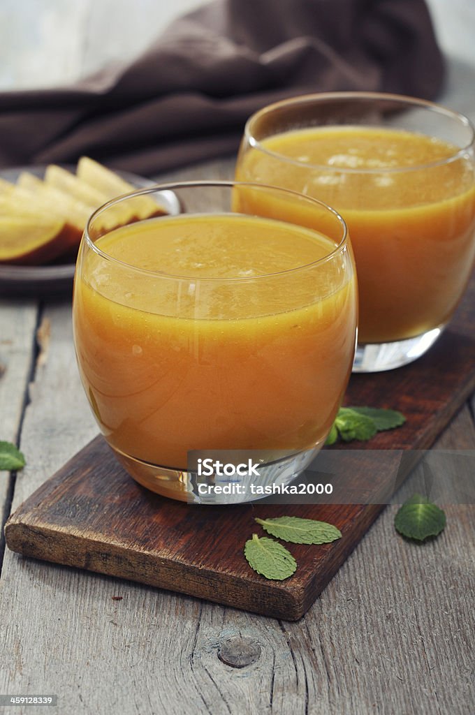 Mango smoothie Mango smoothie in glass with mint on wooden background Blue Stock Photo