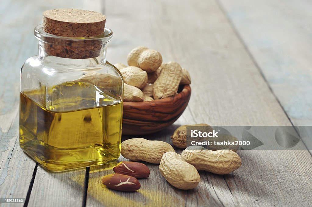 Peanut oil Peanut oil with raw peanuts on wooden background Peanut - Food Stock Photo