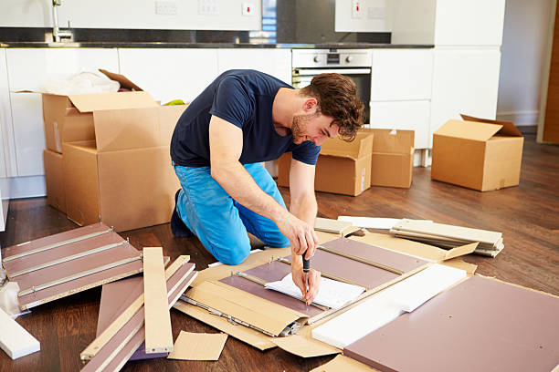 Man in kitchen of new house assembling furniture