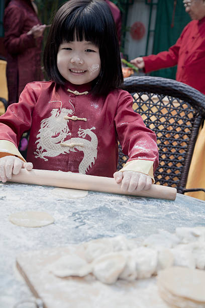 porträt von kleines mädchen macht knödel in traditioneller kleidung - chinese dumpling vertical dumpling asian culture stock-fotos und bilder