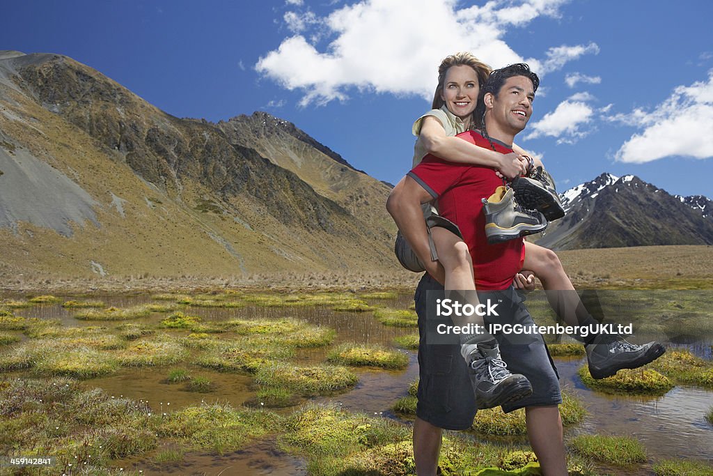 Homem dando mulher levando através do lago de montanha - Foto de stock de Adulto royalty-free