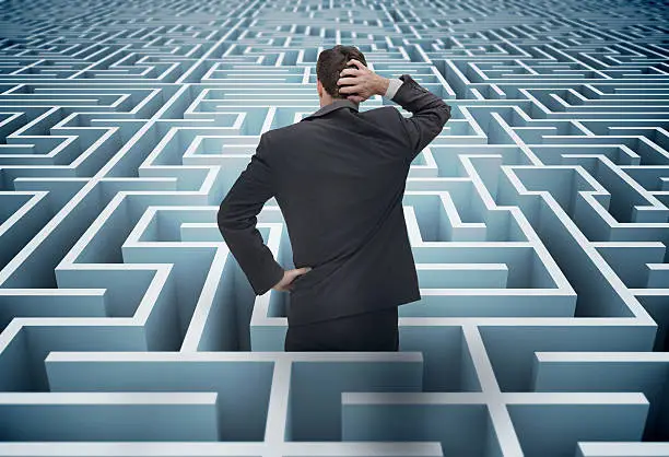 Back of a puzzled businessman getting lost in a huge maze