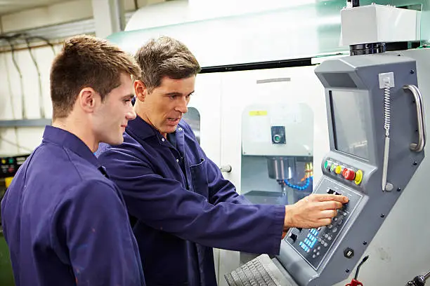 Trained Engineer And Apprentice Using Automated Milling Machine Together