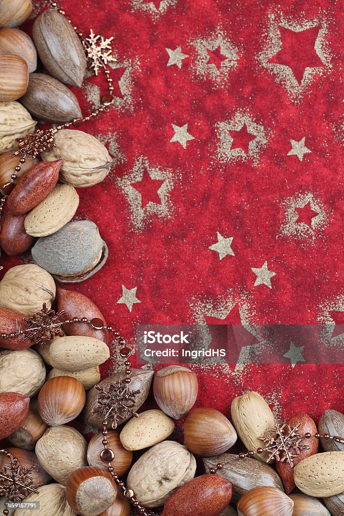 Nut Christmas border Christmas border with various kinds of nuts and Christmas chain on red background.  Almond Stock Photo