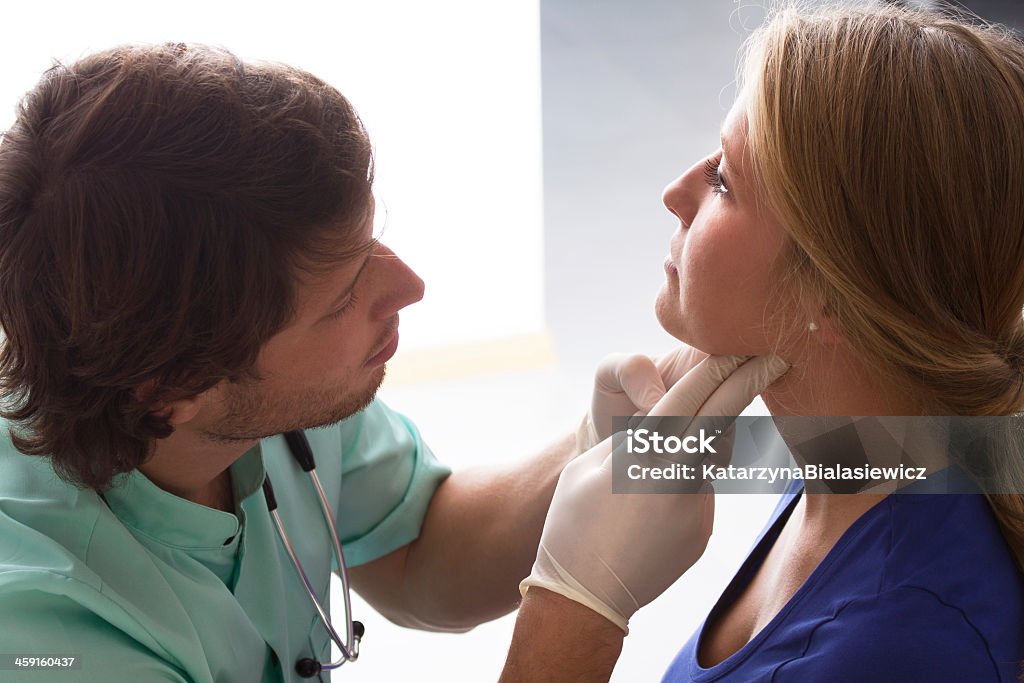 GP examining woman GP examining young woman, who has problems with throat Thyroid Exam Stock Photo