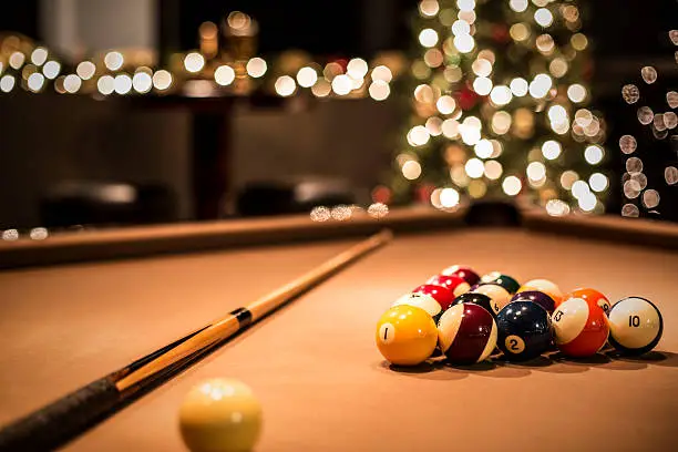 A pool table ready for play, with a festive Christmas environment defocused in the background.
