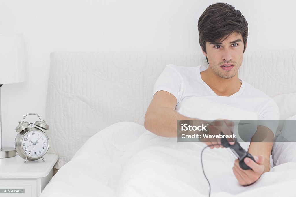 Young man sitting in bed playing video games - 로열티 프리 20-29세 스톡 사진