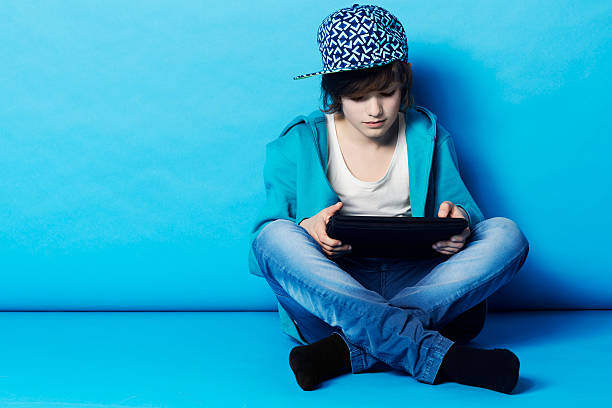 Surfing the web on his tablet A young boy sitting on his digital tablet in the studio kid sitting cross legged stock pictures, royalty-free photos & images