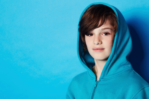 Portrait of a young boy wearing a blue hoodie in the studio