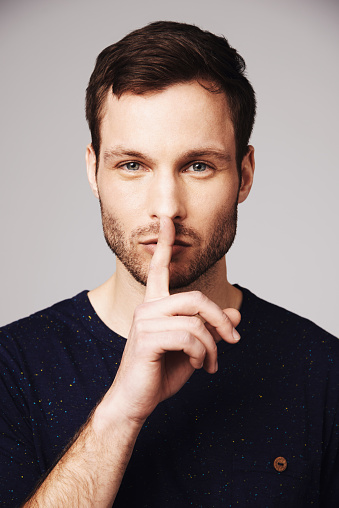 Portrait of a handsome young man with his finger on his lips