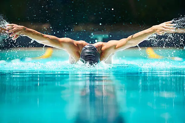 Shot of a male swimmer doing the butterfly stroke toward the camera
