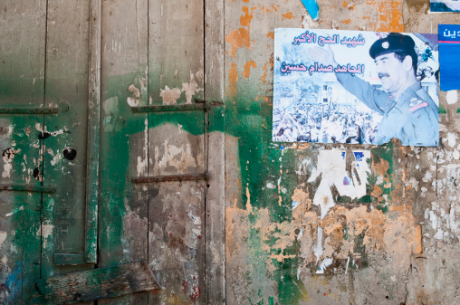 Tripoli, Lebanon - September 7, 2010: A faded poster of executed Iraqi leader Saddam Hussein on a wall. The Arabic can be translated as: “The great martyr and pilgrim, Allah’s warrior, Saddam Hussein”. He was executed on December 30, 2006.