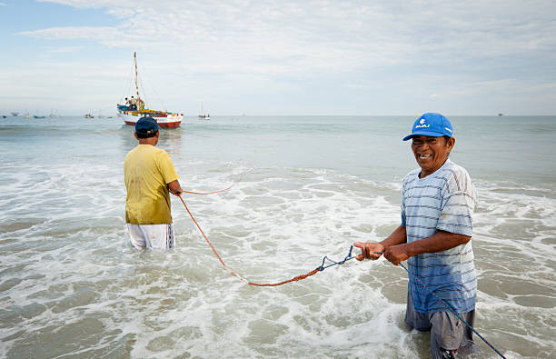 Peruvian fishermen working together to haul their boats in stock photo