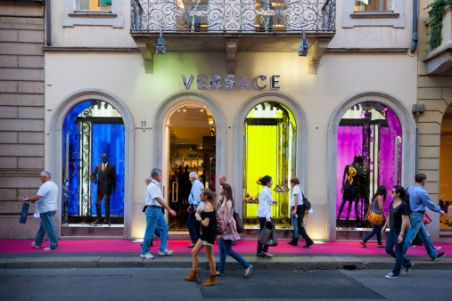 Milan, Italy - October 1, 2011: Tourists and Shoppers walking along the colorful illuminated Versace Store in Milan, Via Montenapoleone 11 Street.