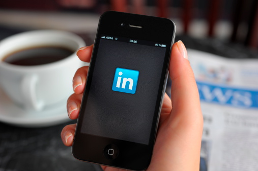 Astanbul, Turkey - December 14, 2011: Woman hand holding an touching an Apple iPhone 4 in a coffee shop. iPhone 4 displaying start up screen of LinkedIn application. The iPhone 4 is a touchscreen slate smartphone and the fourth generation iPhone, developed by Apple Inc.