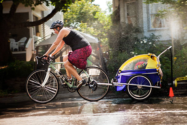 Portland, Oregon, USA - August 28, 2011: A female cyclist rides on the street with a child and cools off in a roadside fountain during Portland Sunday Parkways. It is a free summertime event that occurs on two Sundays in Portland.  It was formed to promote healthy active living and as an opportunity to meet neighbors.  A route through neighborhood streets is open to people, walking, cycling, and rolling and other forms of active transportation.