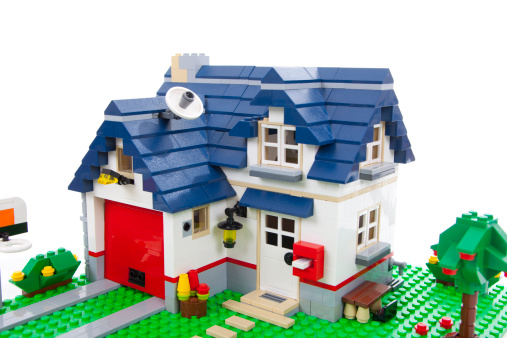 Merano, Italy - July 29, 2011: Lego house made of plastic blocks on white background. The Lego group is a toy producer in Denmark.