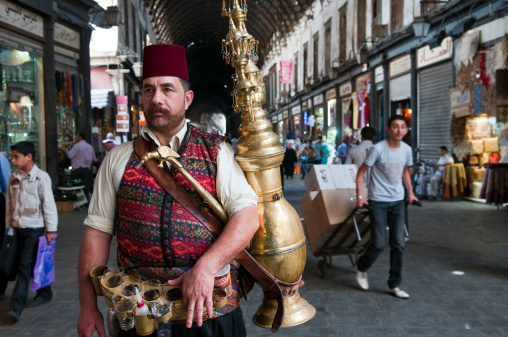 Damascus, Syria - June 6, 2010: A juice seller, probably serving tamarind juice, stands waiting for customers at the Al-Hamidiyeh Souk.