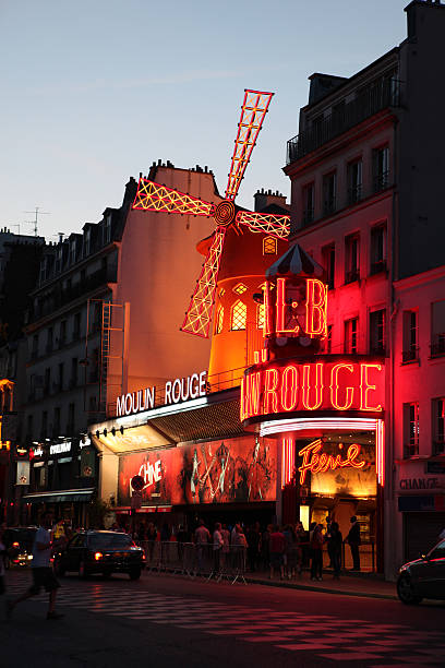 Le Moulin Rouge at the dusk Paris, France - July 31, 2011: Le Moulin Rouge(Red Mill) is a cabaret built in 1889. It\'s situated near Montmartre in the district of Pigalle in the 18th arrondissement of Paris. On this picture le moulin rouge is at the dusk with cars and people waiting in line for this cabaret. place pigalle stock pictures, royalty-free photos & images