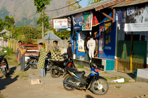 Sembalun, Lombok, Indonesia - August 15, 2011: Customers of a small shop in Sembalun waiting outside. It's cold since the village is already high and it's evening hours. Sembalun is very near to the mighty Rinjani mountain.