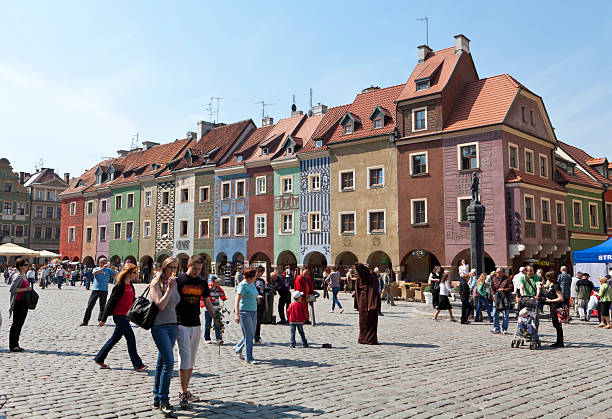 Poznan, Poland- April 26, 2011:People walking  along renovated merchants row houses in Old Market Square in Poznan. Many of the newly renovated row houses contain restaurants,cafes, bars as well as some small shops with souvenirs and jewelry.