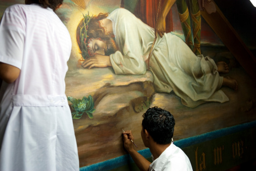 Leon, Nicaragua - November 17, 2008: A man and woman work to restore one of the fourteen paintings by Nicaraguan artist Antonio Sarria, which were done in the late 19th and early 20th centuries and depict the Stations of the Cross. The paintings -- and this restoration work -- are inside the Leon Cathedral, which in 2011 was named a UNESCO World Heritage Site.
