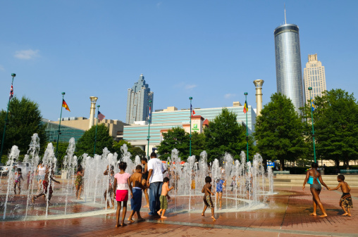 Atlanta, GA, USA - August 3, 2011: Children play in the Olympic ring fountain at Centennial Olympic Park on a hot summer day. The park was built for the 1996 Olympic games and continues to draw visitors, especially in summer. The cylinder-shaped building in the background is the Westin Peachtree Plaza.