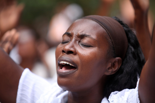Cap Haitian, Haiti - February 6th, 2010: A young Haitian woman, dressed in white, sings and prays with her eyes closed as she takes part in the peace march that was held for the people who perished and suffered in the massive earthquake that caused much destruction in Haiti.The 2010 Haiti earthquake was a catastrophic magnitude 7.0 Mw earthquake which caused massive destruction in Haiti.
