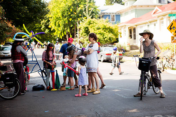 Portland, Oregon, USA - August 28, 2011: A group of cyclists and other people from the neighborhood gather during Portland Sunday Parkways to watch two people twist balloons into interesting mini sculptures.  It is a free summertime event that occurs on two Sundays in Portland.  It was formed to promote healthy active living and as an opportunity to meet neighbors.  A route through neighborhood streets is open to people, walking, cycling, and rolling and other forms of active transportation.