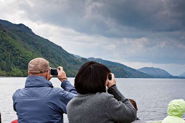 Loch Ness Tourists Loch Ness, Fort Augustus, Scotland, UK - August 24th, 2011:  Tourists capturing the sights on their cameras of Loch Ness while out on the Royal Scot cruise boat. fort augustus stock pictures, royalty-free photos & images