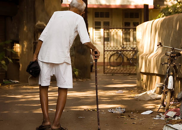 Mumbai, India - Nov 24, 2008.  An old indian man walks through the slums of Mumbai.