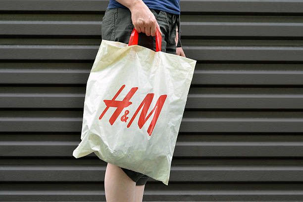 H&M Shopping Vancouver, Canada -- August 21, 2011:Close up of a woman holding an H&M shopping bag.  H&M is a Swedish based clothing retailer that has stores around the world. h and m stock pictures, royalty-free photos & images