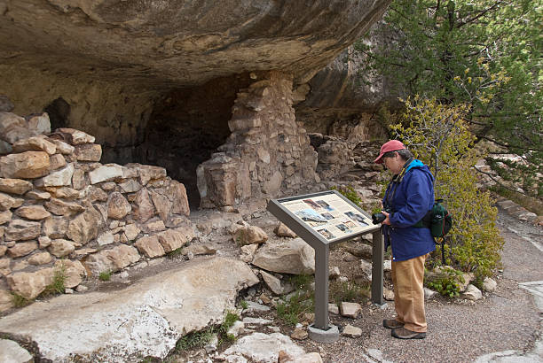 女性ハイカー表示の古代遺跡穴居住居 - walnut canyon ruins ストックフォトと画像