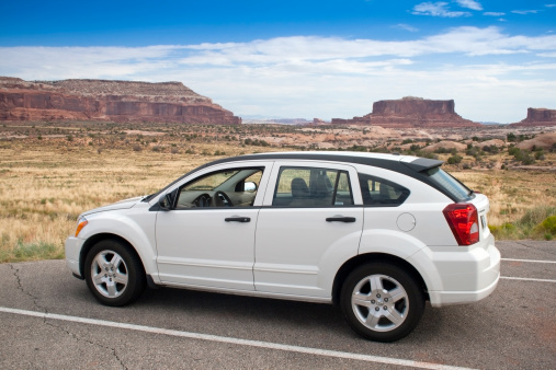 MOAB, USA - August 18, 2007: A white Dodge Caliber parked at a viewpoint on the road to Canyonlands National Park. Stone Mountains on background.