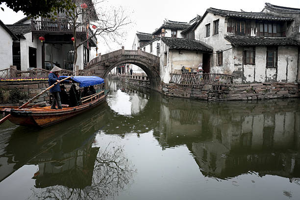 Ancient canal town of Zhouzhuang Zhouzhuang, China - February, 15th 2011:Zhouzhuang is located in Kunshan City, Jiangsu Province, China. Tourtist taking a Sampan boat ride on the canal. Zhouzhuang was built around 1,000 years ago, it is one of the most famous canal towns in China and attracts thoudsands of tourist daily. grand canal china stock pictures, royalty-free photos & images