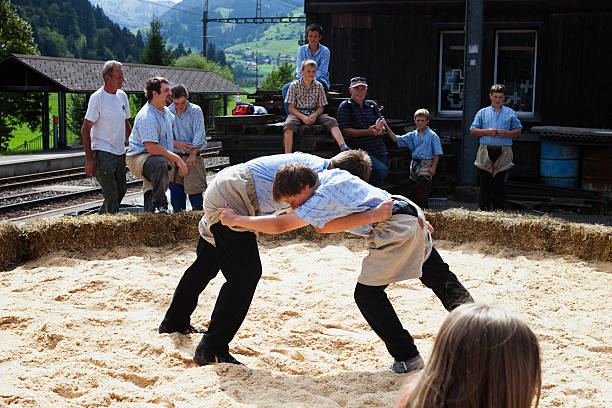 Boltigen, Switzerland - September 3, 2011: Two young teenagers begin a wrestling match, Boltigen, Simmental.  They are wrestling on a sawdust ring next to the train station in Boltigen.  Boltigen is located in the Bernese Oberland, Switzerland  in the Simmental where the road from the Jaun Pass reaches the floor of the Simmen valley. It is an agricultural village, and periodically holds a farmer's market on the square next to the train station. The market is frequented primarily by local people.