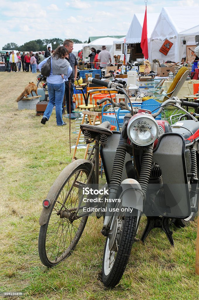 Bicicleta y motorcycle on flea market con los visitantes en el fondo - Foto de stock de Aire libre libre de derechos