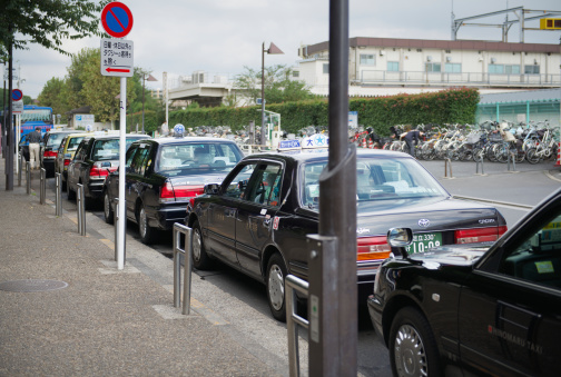 Tokyo, Japan - October 7, 2013: Taxi waiting area near the Ueno Park in Tokyo. Several taxi cabs are waiting in line along the sidewalk. A man is entering the taxi in front of the line.