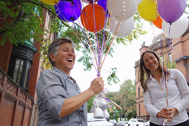 Two females smiling while holding balloons stock photo