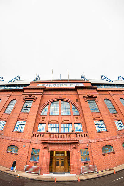 Ibrox Stadium, Glasgow Glasgow, UK - October 20, 2013: A woman walks along the street in front of the Bill Struth Main Stand at the main entrance to Ibrox Stadium, Glasgow, the home ground of Rangers Football Club. The main stand was built in 1928 with an impressive red brick facade. ibrox stock pictures, royalty-free photos & images