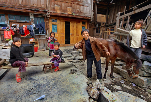 Zengchong village, Guizhou, China - April 12, 2010: Asian family in the countryside of southwestern China, a father and his four children, and relax in front of his wooden house in the peasant economy, April 12, 2010. Zengchong village, Guizhou, China