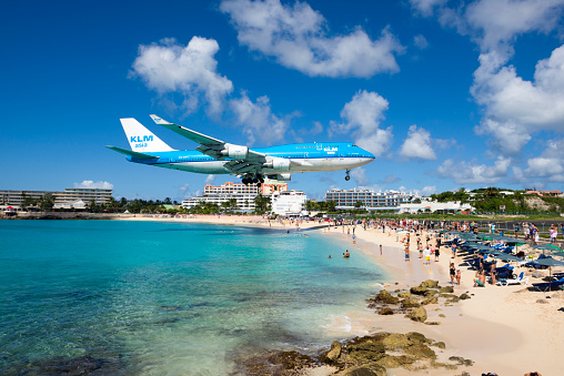 Maho Bay, St Maarten, Netherlands Antilles - November 15, 2013: People at Maho Beach watch a KLM Boeing 747 come in for a landing at Princess Juliana International Airport in St. Maarten.