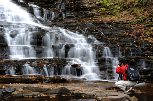 Benton, USA - October 13, 2013. A man photographing waterfalls in Ricketts Glen State Park. Ricketts Glen State Park is located in Benton, Pennsylvania. It attracts lots of visitors for its scenic waterfalls.