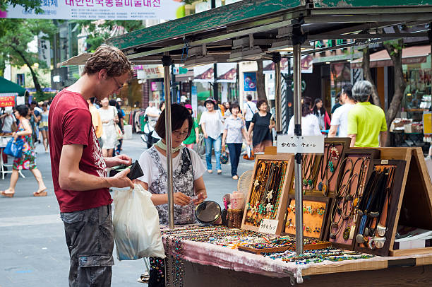 Seoul, South Korea - August 17, 2013: A tourist pays for some jewelry at a street vendor in Insadong, Seoul. Insadong is a popular tourist destination in Seoul that offers a variety of traditional crafts and goods, along with the usual souvenirs.
