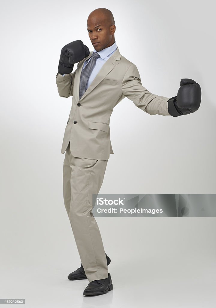 Ready for a business fight An ethnic man standing in a suit with boxing gloves on Adult Stock Photo