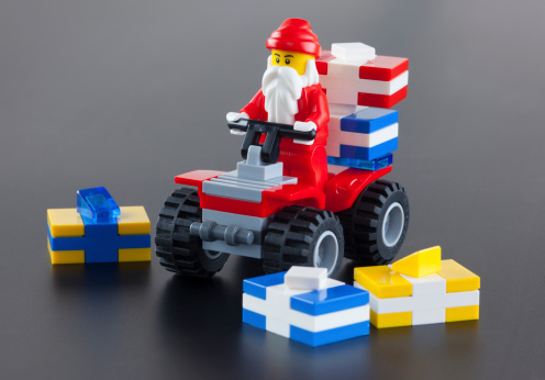 Tambov, Russian Federation - October 04, 2013: Lego Santa Claus minifigure on red quadrocycle with gift boxs on black background. Studio shot.