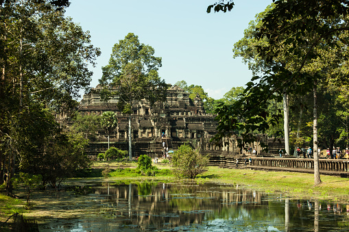 Angkor, Cambodia - December 9, 2012: Tourists are visiting the Baphuon temple in Angkor, Cambodia. Built in the 11th century, the temple has collapsed under the ages. It restoration started in 1960 and after a few attempts has been completed in 2011.