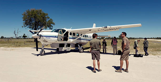 To the next destination Selinda Concession, Botswana - April 1, 2012: Airstrip with stationary airplane Cessna 208B Grand Caravan . Two pilots and tourists are waiting for the plane to leave to their next destination in the Okavango Delta. bush plane stock pictures, royalty-free photos & images